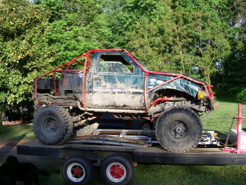 1985 Ford Bronco - This heavily modified off-road truck, covered in mud, is loaded onto a trailer.