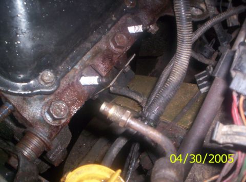 1985 Ford Bronco - Close-up view of spark plugs in an engine block, with visible rust and wiring harnesses.