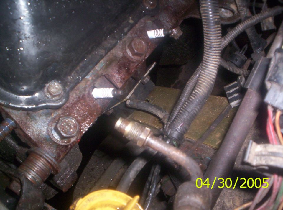 Engine block with spark plugs installed, showing some rust and wiring