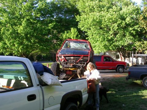 1985 Ford Bronco - Multiple trucks are visible in an outdoor setting, with one heavily modified truck being transported.