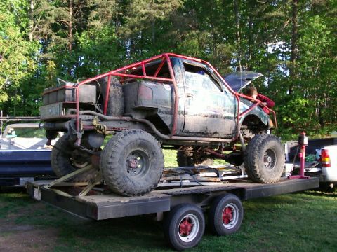 1985 Ford Bronco - Custom off-road truck with extensive modifications is being transported on a trailer.