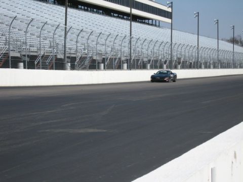 1991 Ford LTD Crown Victoria - A black coupe drives on a race track in front of empty grandstands.