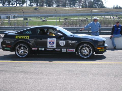1991 Ford LTD Crown Victoria - A black Ford Mustang GT sits on a racetrack with two men standing nearby.