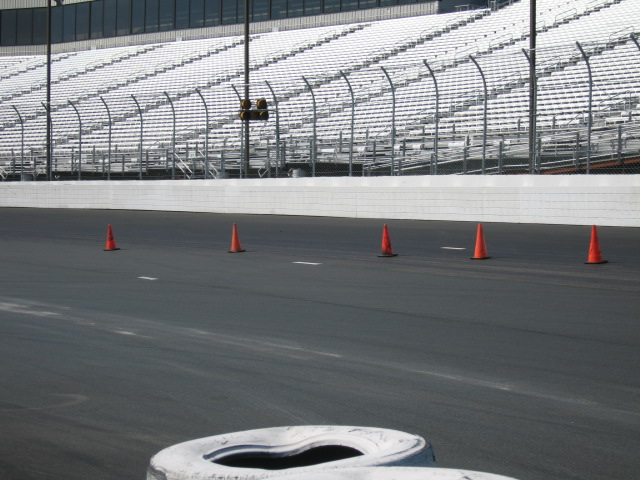 Race track with orange cones and empty white bleachers in the background