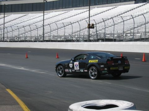 1991 Ford LTD Crown Victoria - A black Ford Mustang with racing decals and the number 33 is seen on a race track with grandstands in the background.