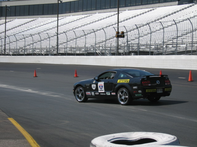 Black Ford Mustang with racing decals on a track, 3q-front view