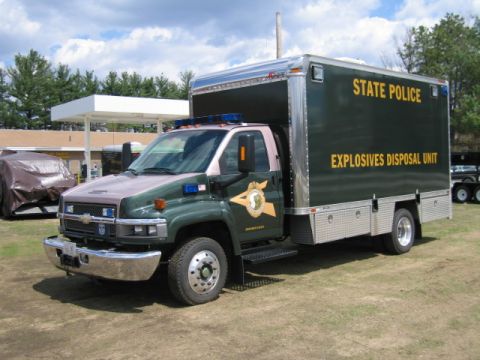 1991 Ford LTD Crown Victoria - A state police truck, marked as the Explosives Disposal Unit, is parked on a grassy area with a gas station canopy in the background.