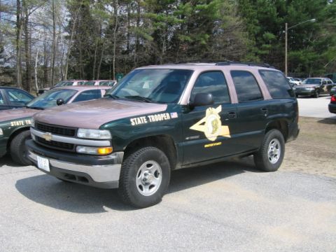 1991 Ford LTD Crown Victoria - A green and tan Chevrolet Tahoe, marked as a state trooper vehicle, is parked alongside other patrol cars.
