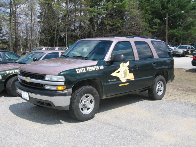 Green and tan Chevrolet Tahoe, side view, with "STATE TROOPER" text and badge