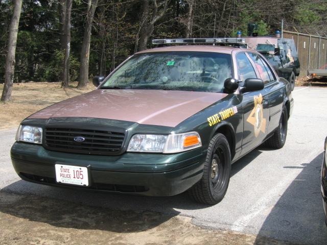 Green and tan Ford Crown Victoria Police Interceptor with State Police markings, parked outside