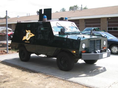 1991 Ford LTD Crown Victoria - An armored vehicle with blue lights on top is parked next to other vehicles.