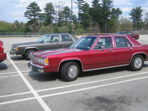 1991 Ford LTD Crown Victoria - Front three-quarter view of a maroon boxy Ford full-size four-door sedan parked in a paved lot, with body-side molding, dog-dish-style whee…