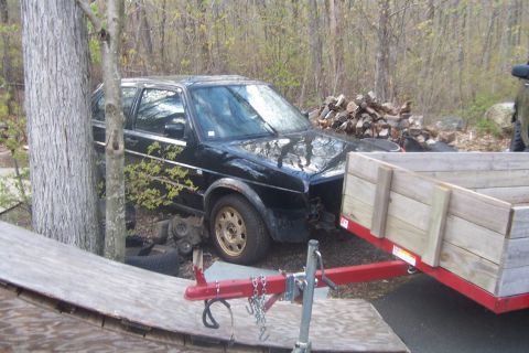 1996 Ford Bronco - A black hatchback car, appearing to be a Volkswagen Golf, is parked outdoors with a trailer nearby.