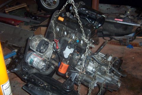 1996 Ford Bronco - Engine assembly, likely out of a vehicle, is suspended by chains with an oil filter attached.