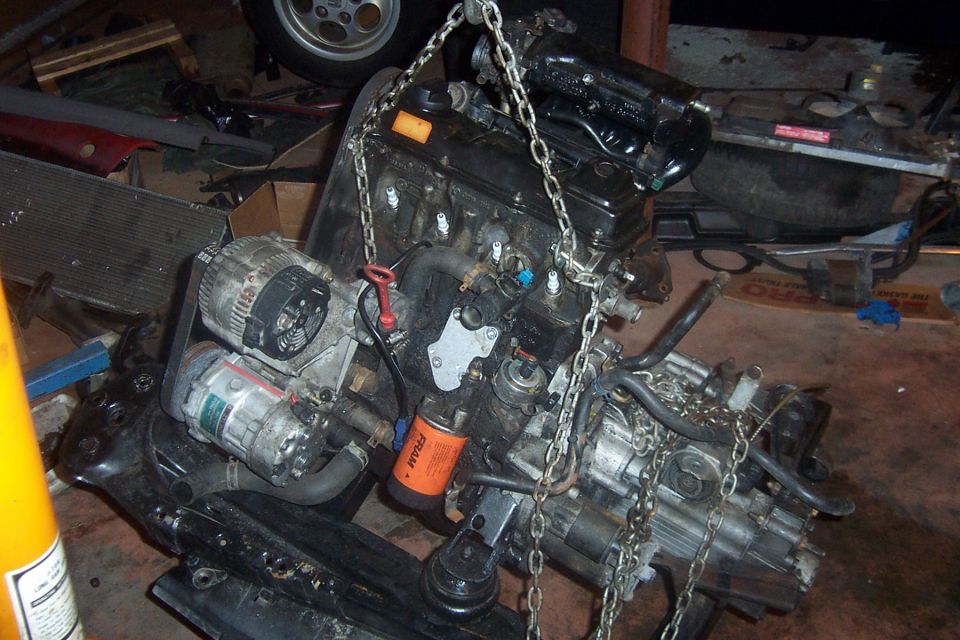 Engine assembly suspended by chains, with oil filter visible