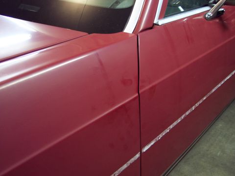 2001 Ford Crown Victoria - Close-up view of the side of a red 2001 Ford Crown Victoria, showing the fender and door panel.