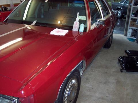 2001 Ford Crown Victoria - A red sedan is parked in a garage, with another vehicle visible in the background.