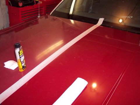 2001 Ford Crown Victoria - A red car hood is prepped for detailing with masking tape and a bottle of Goof Off cleaner.