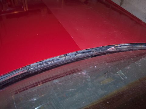 2001 Ford Crown Victoria - Close-up of a red car's hood and windshield wipers, showing wear and dirt.