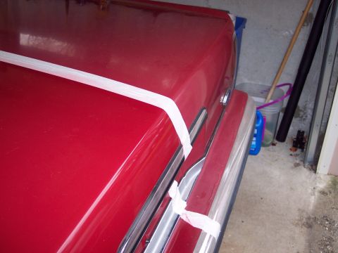 2001 Ford Crown Victoria - A red car is wrapped in plastic and secured with tape, possibly for storage or transport.