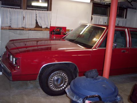 2001 Ford Crown Victoria - A red sedan is parked indoors, showing its front fender and wheel.