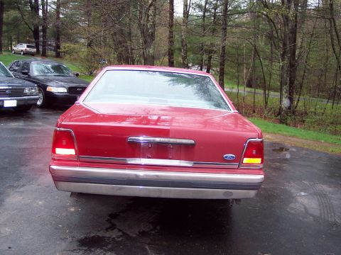 2001 Ford Crown Victoria - Rear view of a red 2001 Ford Crown Victoria sedan parked outdoors with other vehicles nearby.