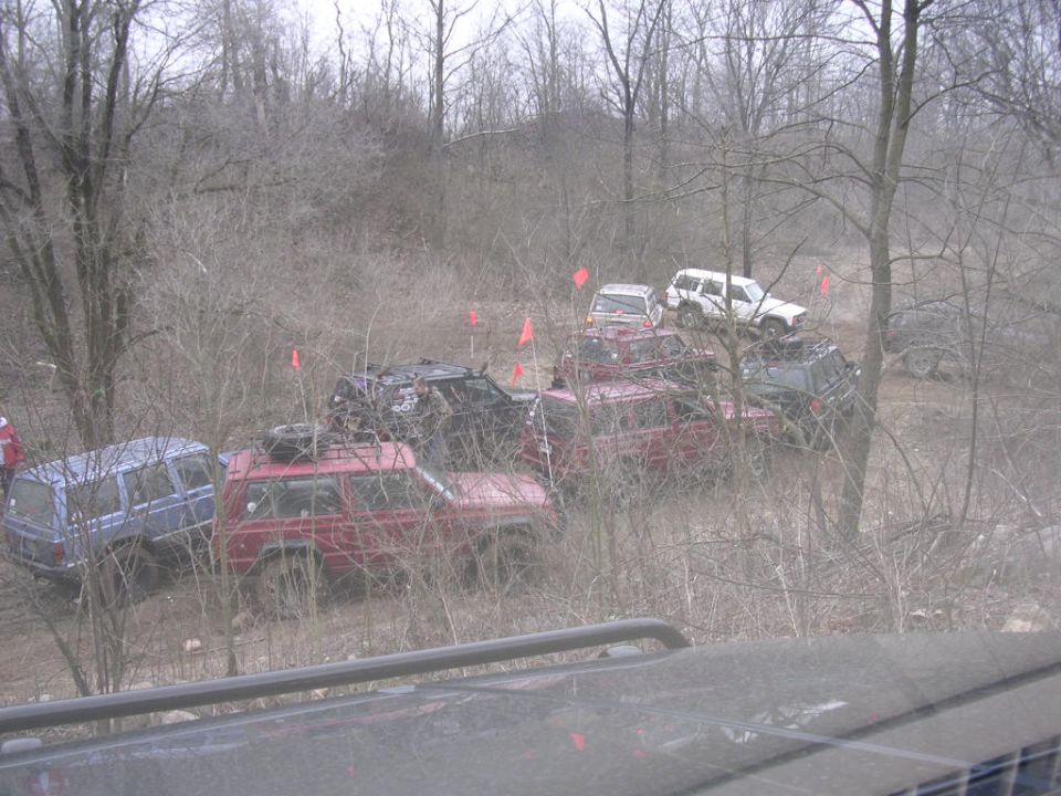 Red and blue SUVs on a dirt path with trees and orange flags