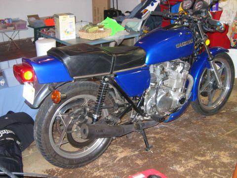 1985 Ford LTD Crown Victoria - A blue Suzuki motorcycle is parked indoors with its kickstand down.