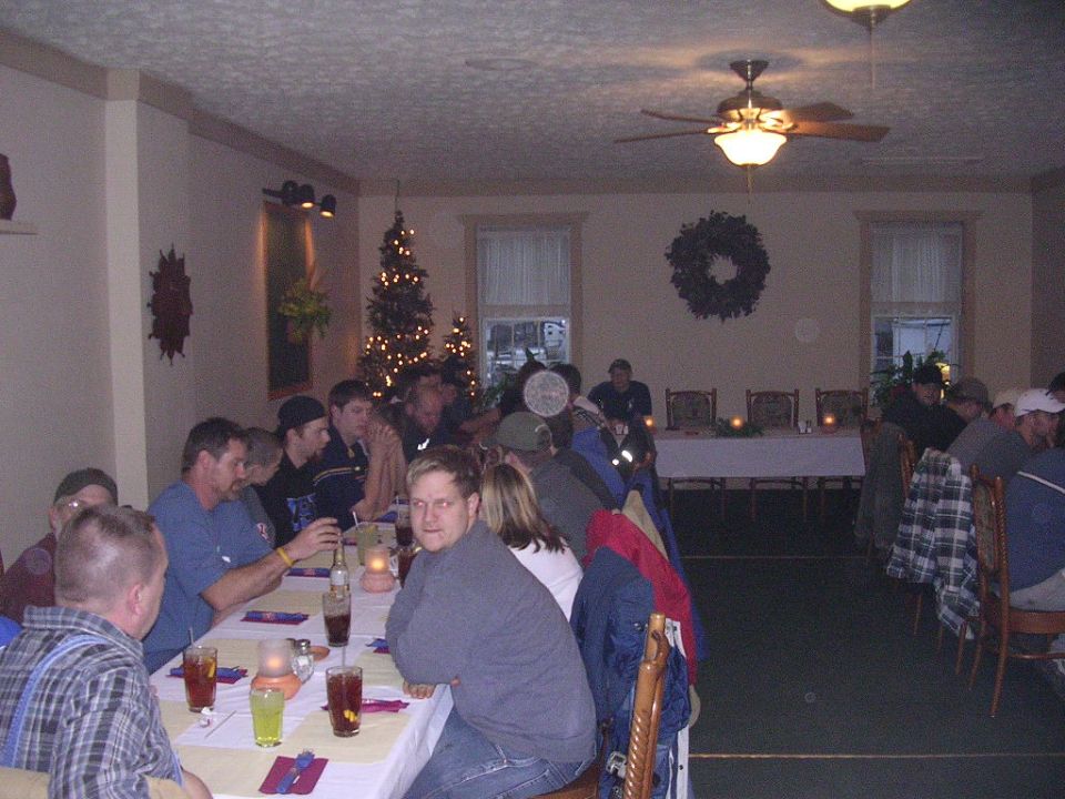 People gathered around tables in a room with Christmas decorations, including a tree and wreaths