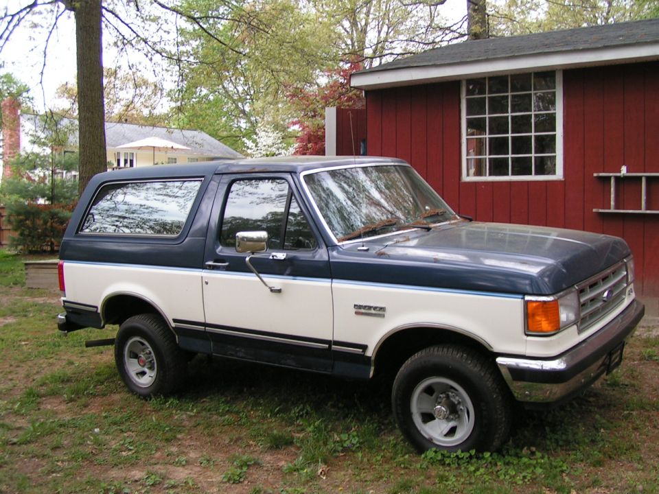 1987 Ford Bronco, two-tone blue and white, parked in a yard