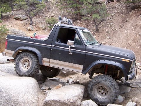 1991 Ford Bronco - This modified Ford Bronco is tackling a challenging rocky terrain on an off-road trail.