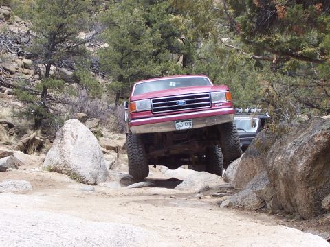 1991 Ford Bronco - 1991 Ford Bronco tackling a challenging rocky trail with another vehicle in the background.