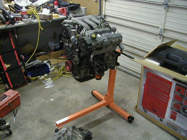 engine on orange stand in garage, tools and toolbox nearby