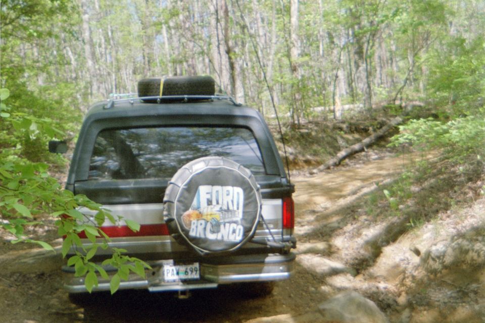 Black Ford Bronco with spare tire cover, driving on a dirt trail