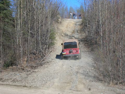 2003 Jeep TJ - A Jeep TJ navigates a steep, dusty off-road trail on a sunny day.