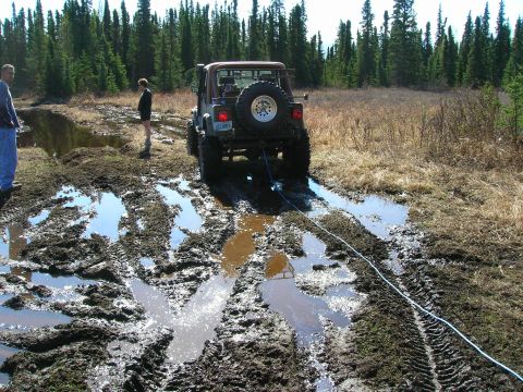 2003 Jeep TJ - A Jeep TJ winches itself out of a deep mud pit on a wooded trail.