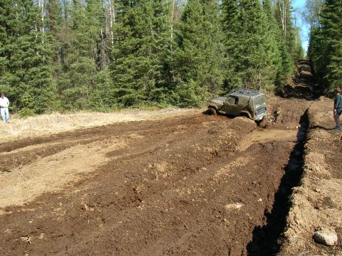 2003 Jeep TJ - A Jeep TJ tackles a challenging muddy off-road course, demonstrating its capabilities in difficult terrain.