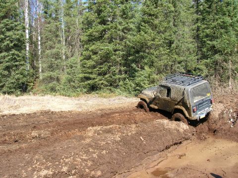 2003 Jeep TJ - A 2003 Jeep TJ navigates a challenging muddy trail, getting stuck in the deep ruts.