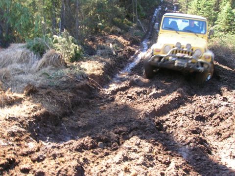 2003 Jeep TJ - Yellow 2003 Jeep TJ off-roading on a muddy track.