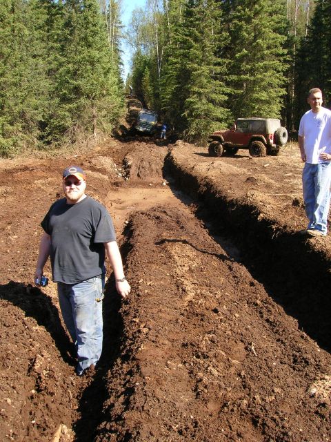 2003 Jeep TJ - Off-road vehicles tackle a challenging muddy course with spectators observing the action.