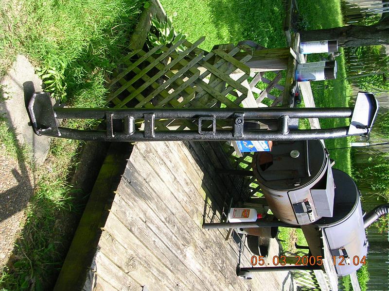 aftermarket rear bumper with hitch receiver, sitting on a wooden deck next to a smoker