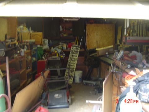 1985 Ford Bronco - This image depicts a disorganized garage space filled with various items, including a lawnmower and tools, with a timestamp in the corner.