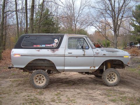 1979 Ford Bronco - This lifted 1979 Ford Bronco features a two-tone paint scheme with a silver body and black hardtop, modified for off-road use.