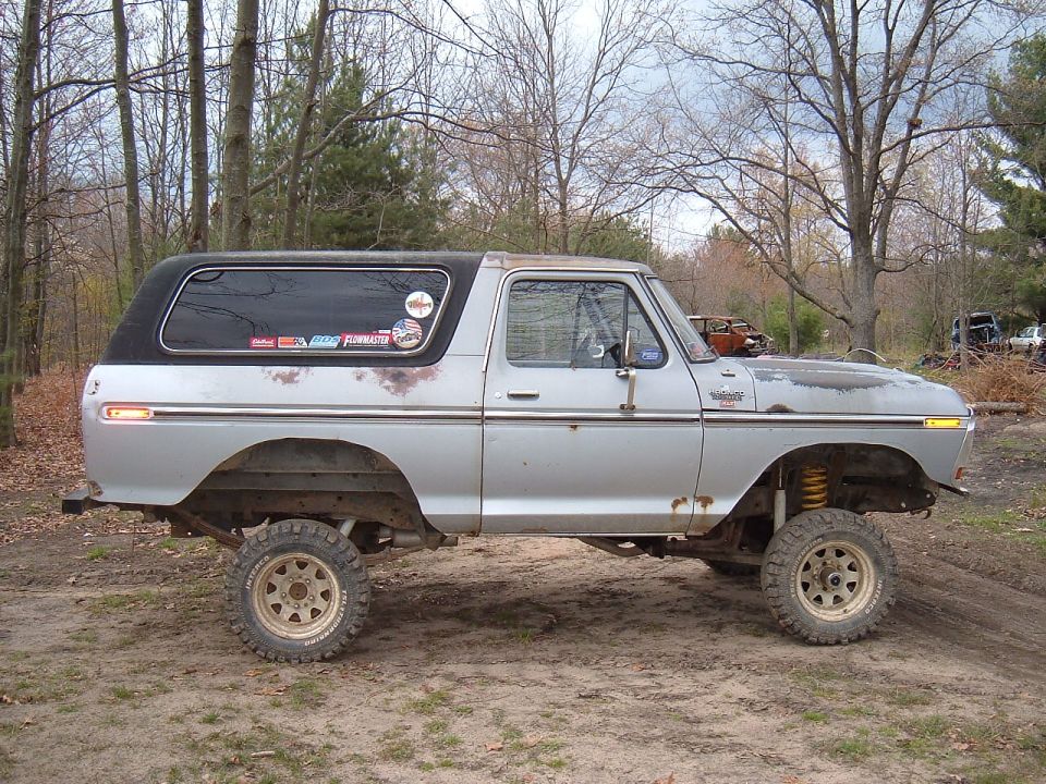 Silver 1979 Ford Bronco side view, lifted with off-road tires and black top