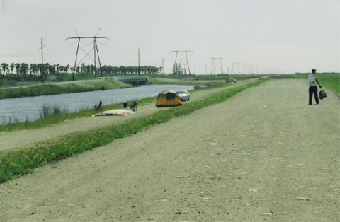 1992 Ford Bronco - A rural scene power lines, a canal, and a person walking on a dirt road.