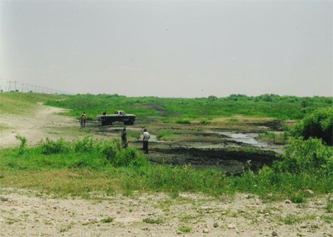 1992 Ford Bronco - A pickup truck is stuck in a muddy area, with several people observing the situation.