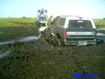 1992 Ford Bronco - A 1992 Ford Bronco is stuck in the mud with a tractor in the background.