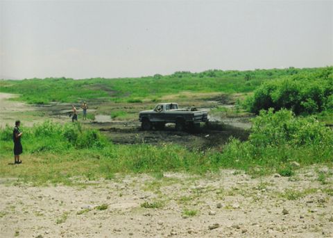 1992 Ford Bronco - A Ford pickup truck is stuck in a muddy field with two people observing.