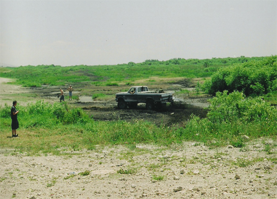 Ford pickup truck stuck in mud with people watching