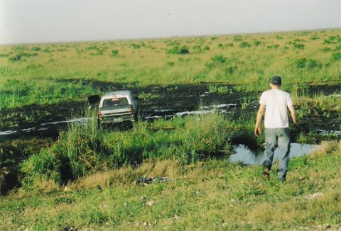 1992 Ford Bronco - A person walks away from a 1992 Ford Bronco stuck in a muddy field.